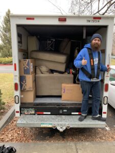 College Movers team member beside a packed moving trailer