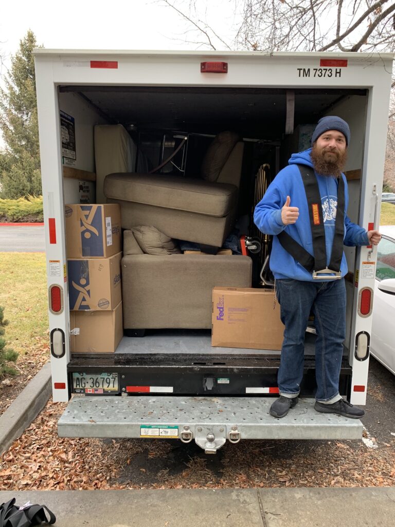 College Movers team member beside a packed moving trailer