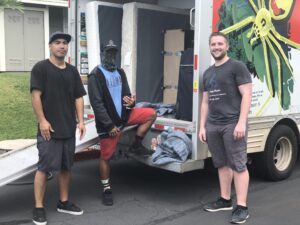 Three College Movers team members beside a moving truck